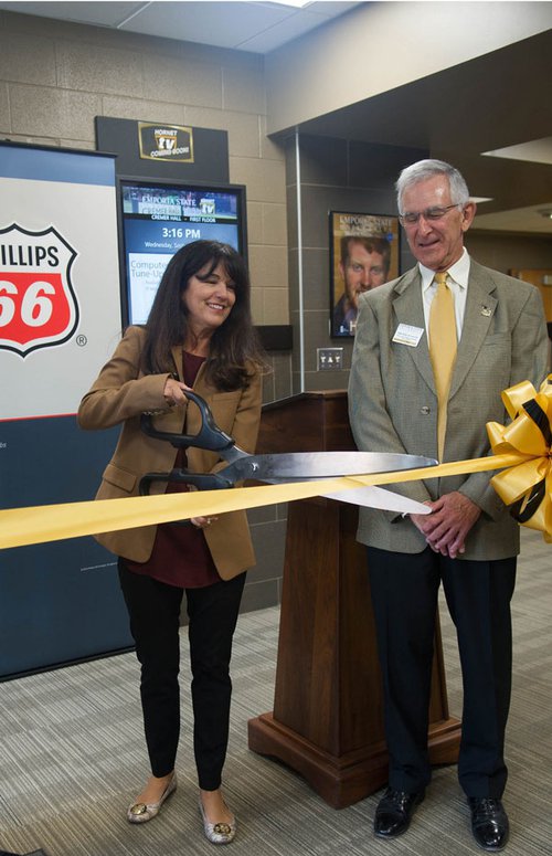 Juli Osborn of Phillips 66 cuts the ribbon on the Phillips 66 Professional Development Suite as Dr. John Rich, interim dean of the School of Business, looks on. 