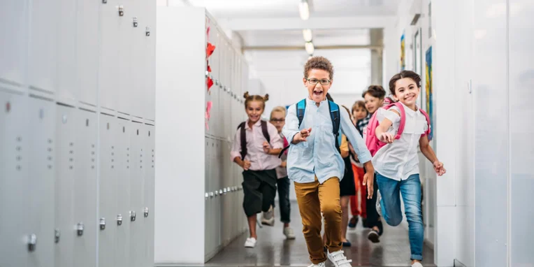 happy elementary aged children running in school hallway